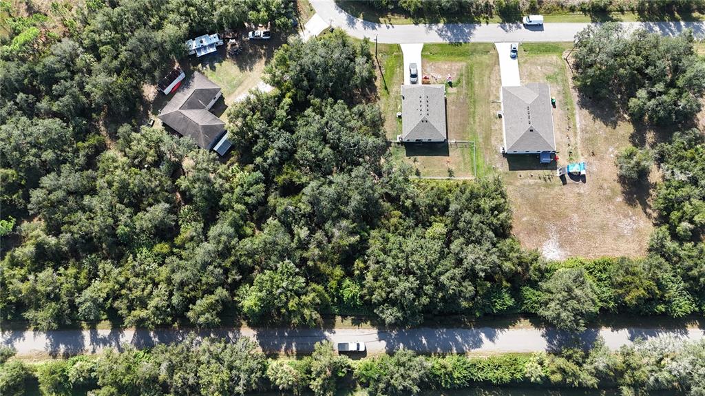 An aerial view shows three houses surrounded by dense trees near two paved roads — 29359 NOTTINGHAM ROAD, PUNTA GORDA, FL