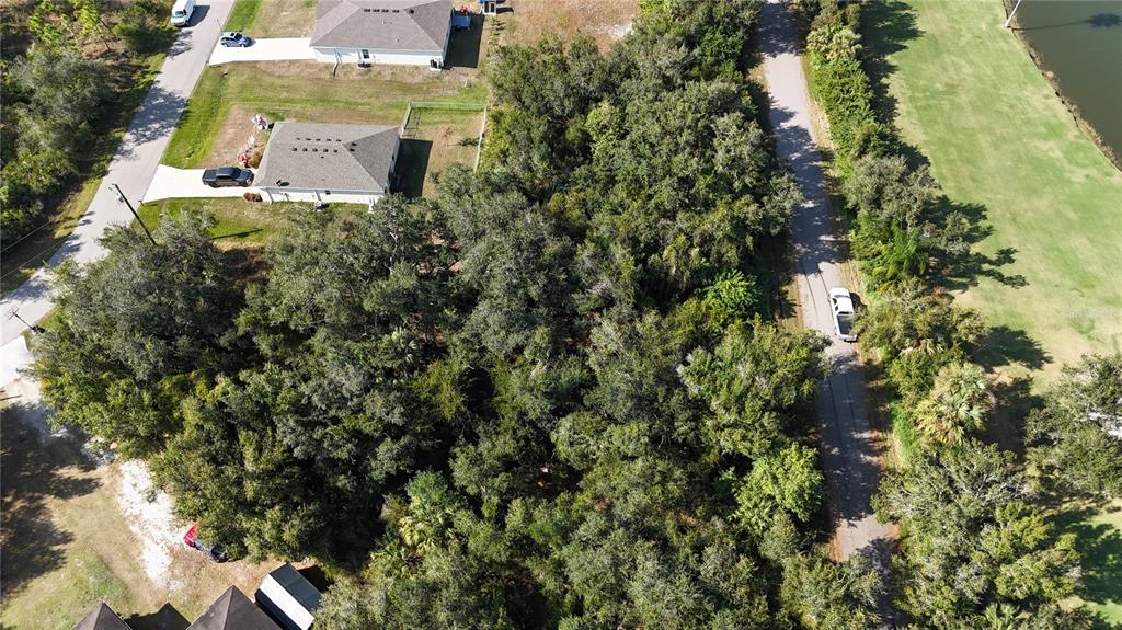 An aerial view shows a wooded lot situated between residential houses and a paved road — 29359 NOTTINGHAM ROAD, PUNTA GORDA, FL