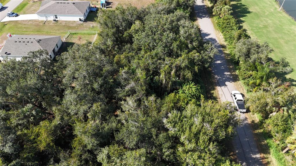 An aerial view shows a wooded lot situated between a residential street and houses — 29359 NOTTINGHAM ROAD, PUNTA GORDA, FL