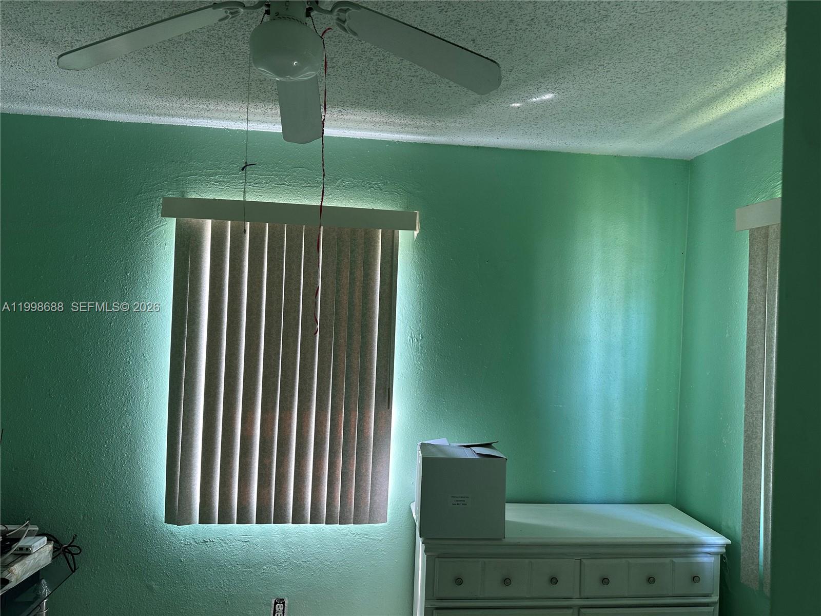 A bedroom features mint green walls, a ceiling fan, vertical blinds, and a white dresser — 900 NW 75th St, Miami FL 33150, MIAMI, FL