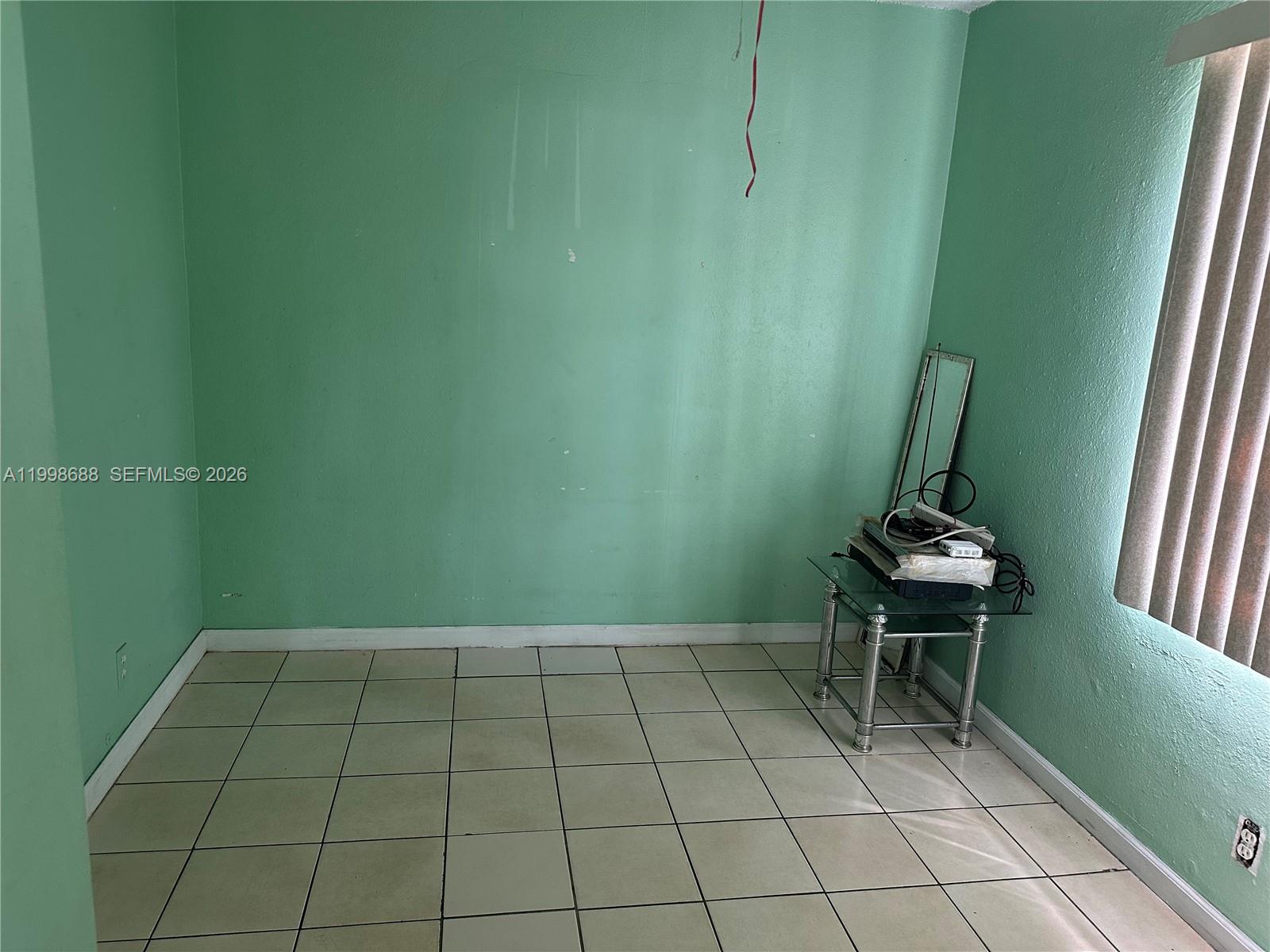A room with mint green walls, tiled flooring, and a glass-topped metal side table — 900 NW 75th St, Miami FL 33150, MIAMI, FL