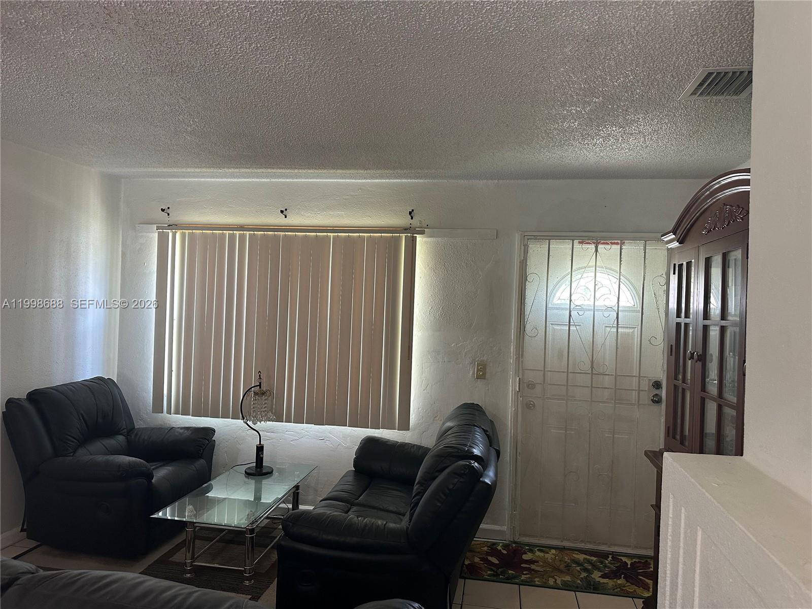 A living room features black leather furniture, a glass coffee table, and a white door — 900 NW 75th St, Miami FL 33150, MIAMI, FL