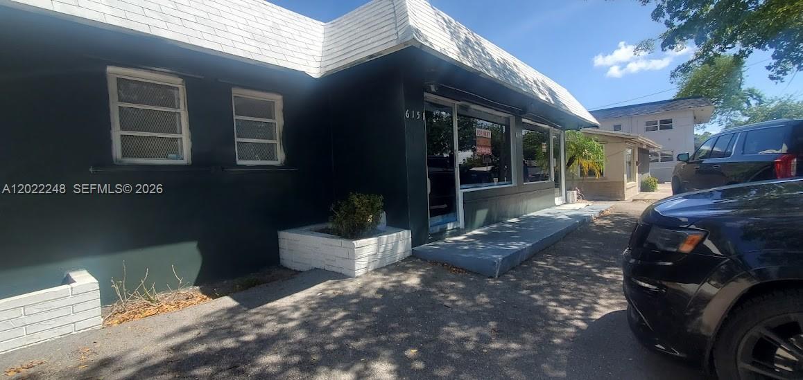 A dark-painted commercial building features a white roof, a front entrance, and a paved lot — 6151 Washington St, Hollywood FL 33023, HOLLYWOOD, FL
