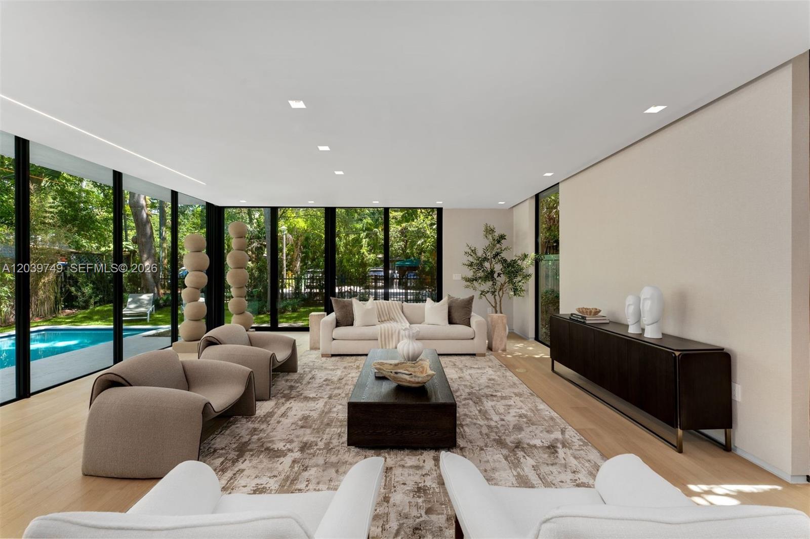A modern living room features floor-to-ceiling windows, a pool view, and neutral-toned furniture — 3579 Avocado Ave, Miami FL 33133, MIAMI, FL