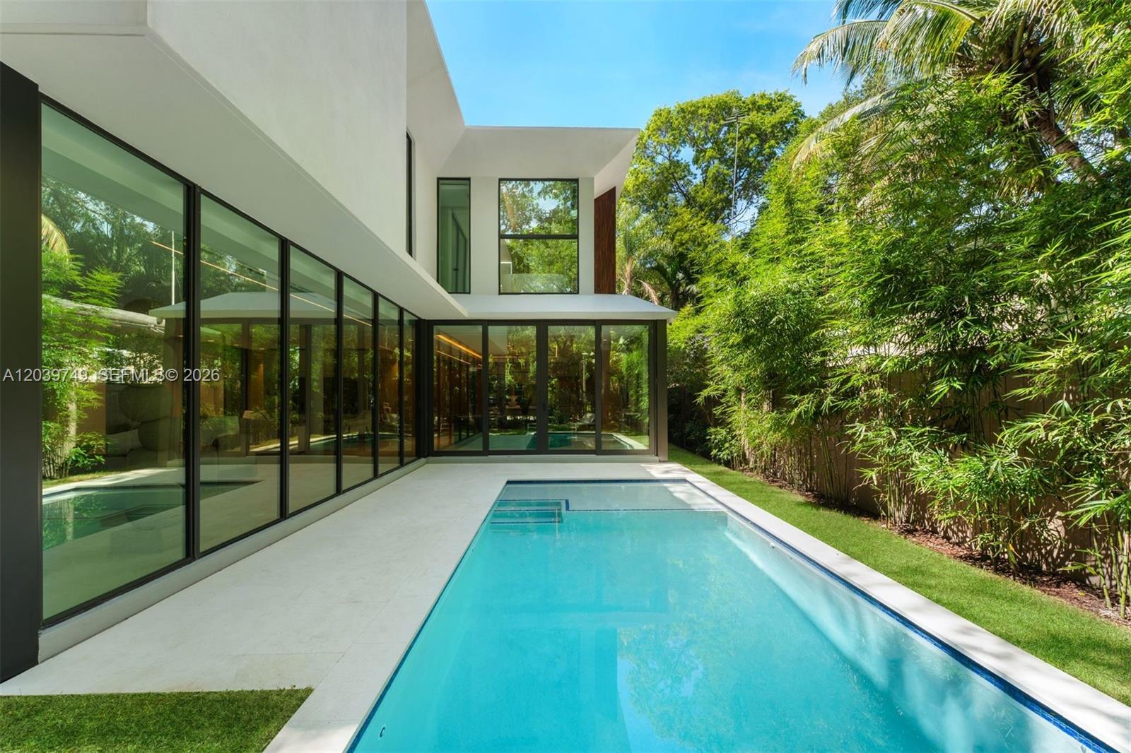 A modern two-story house with floor-to-ceiling windows overlooks a rectangular swimming pool and lawn — 3579 Avocado Ave, Miami FL 33133, MIAMI, FL