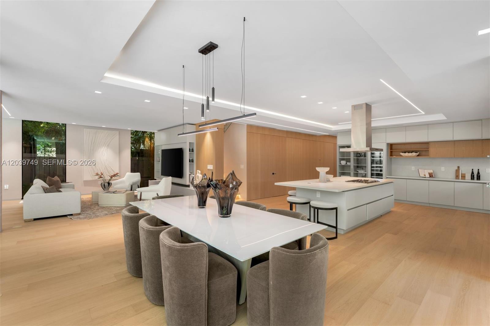 A modern open-concept living and dining area features light wood floors and a kitchen island — 3579 Avocado Ave, Miami FL 33133, MIAMI, FL