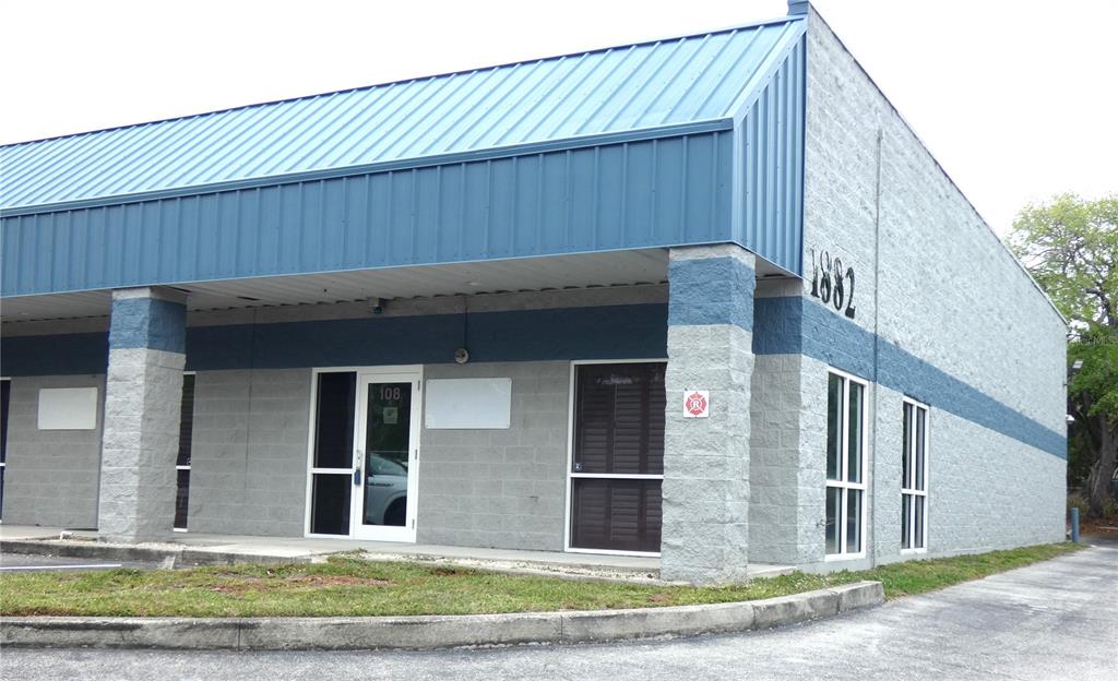 A single-story commercial building with a blue metal roof and gray concrete block walls — 1882 PORTER LAKE DRIVE UNIT 107/108, SARASOTA, FL