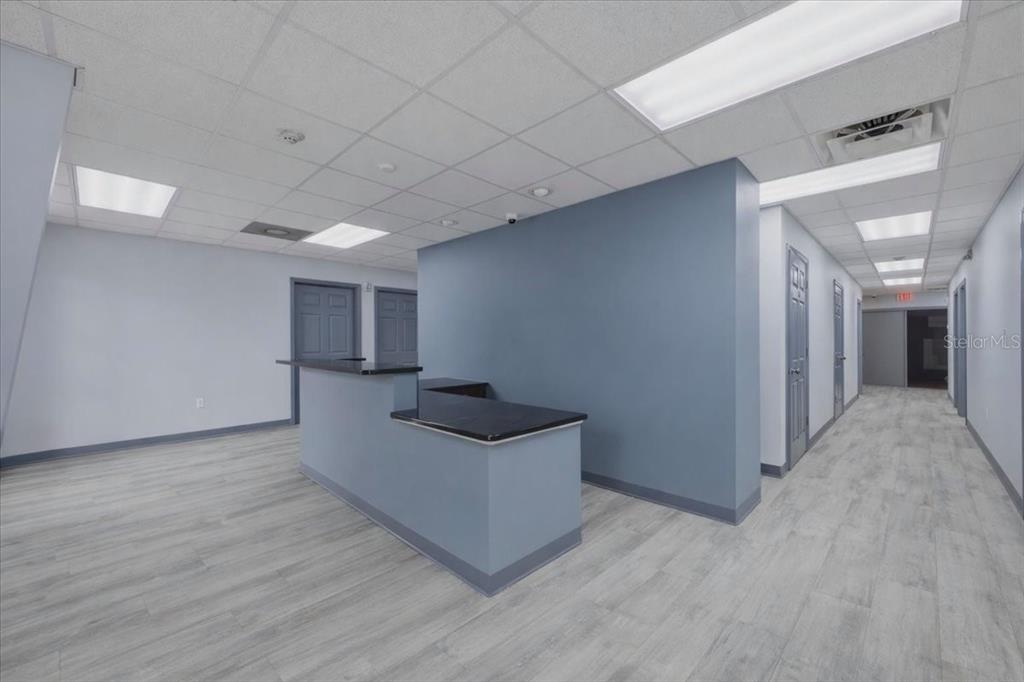 An office reception area features a blue partition wall, a black-topped desk, and light flooring — 1882 PORTER LAKE DRIVE UNIT 107/108, SARASOTA, FL