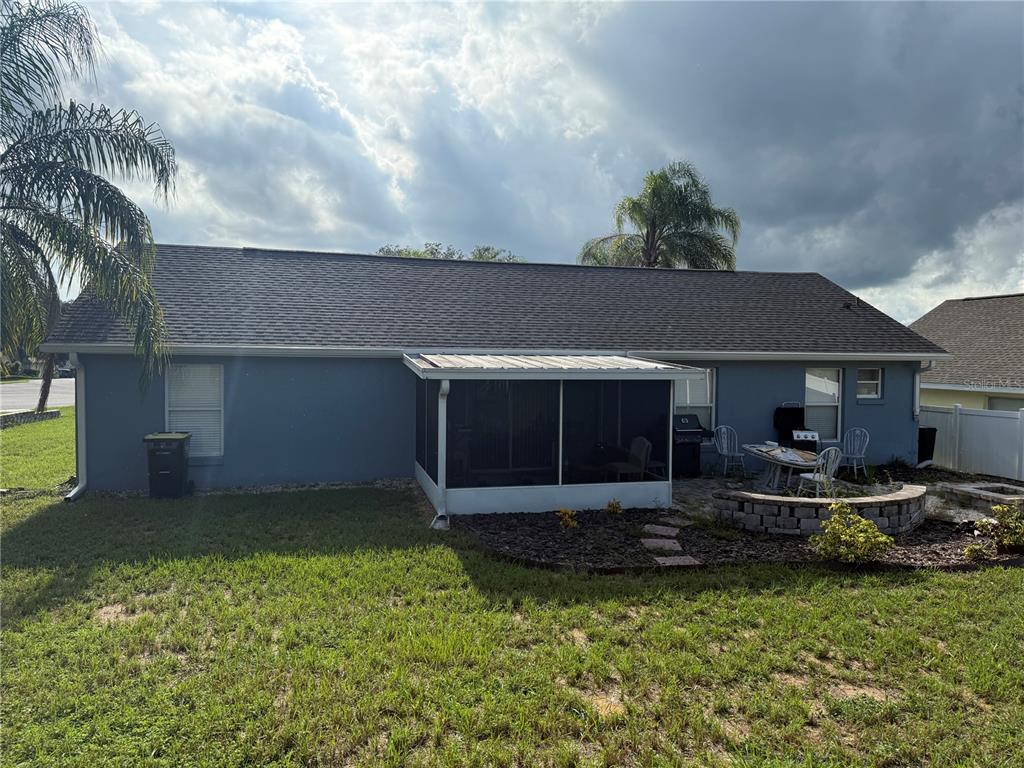 The rear exterior of a blue house features a screened-in porch and a stone patio — 234 MONTANA AVENUE, DAVENPORT, FL