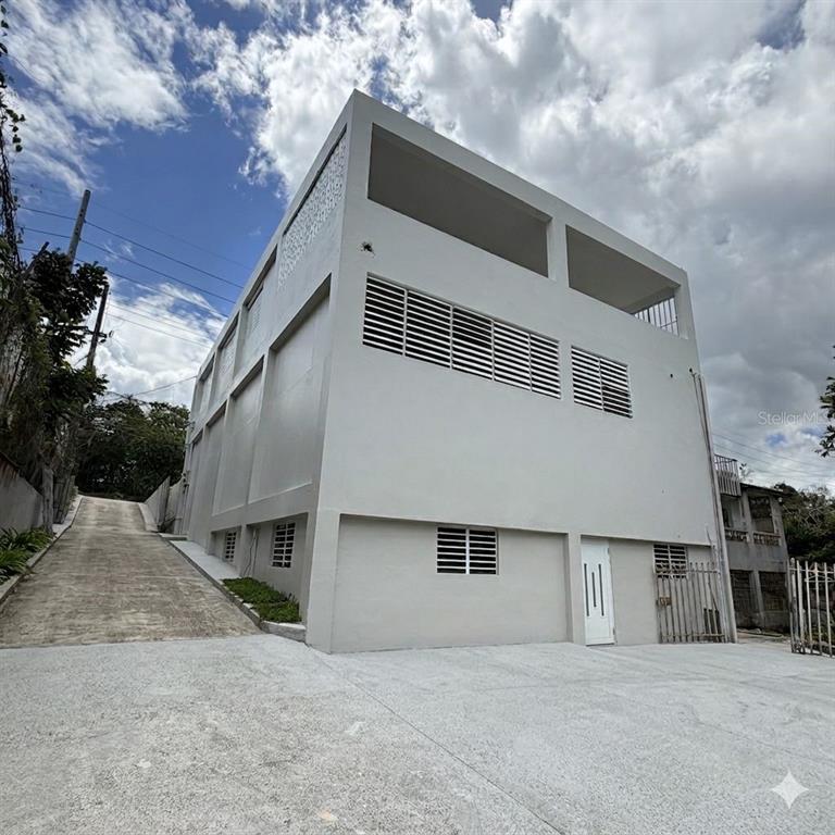 A three-story concrete building with a sloped driveway and white louvered windows — PR-2 CANDELARIA BO ARENAS, TOA BAJA, PR