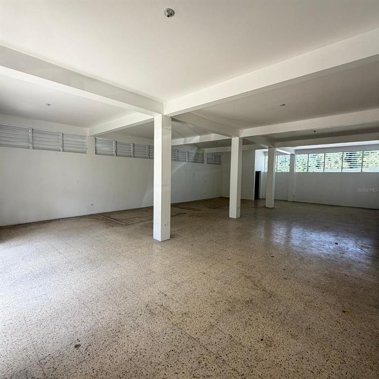 An open, unfinished commercial space features white walls, support columns, and speckled tile flooring — PR-2 CANDELARIA BO ARENAS, TOA BAJA, PR