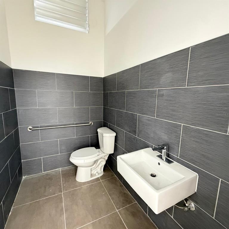 A bathroom features dark gray tiled walls, a white toilet, and a wall-mounted sink — PR-2 CANDELARIA BO ARENAS, TOA BAJA, PR