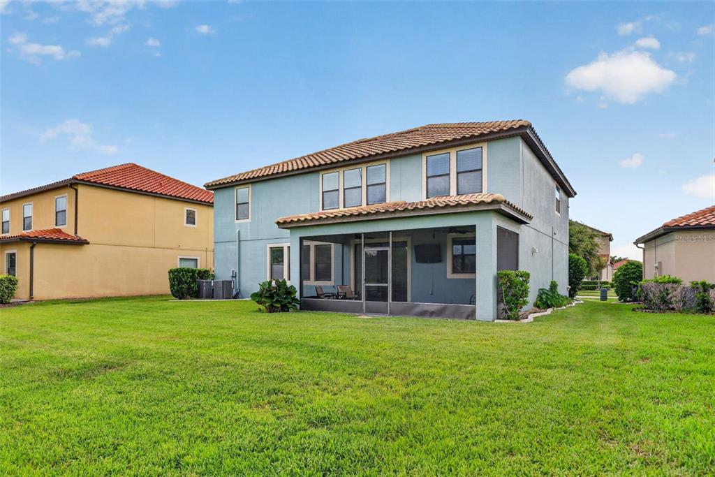 The rear exterior of a two-story house features a screened-in patio and a grassy yard — 11911 SAND MYRTLE ROAD, RIVERVIEW, FL