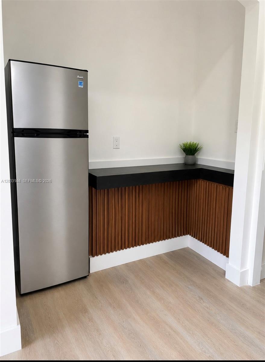 A stainless steel refrigerator stands next to a black countertop with wood-slat paneling — 23041 SW 107th Ave # 2, Miami FL 33170, MIAMI, FL