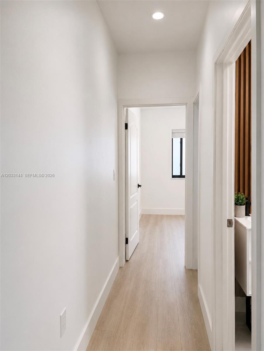 A bright hallway with light wood flooring leads to an open doorway and a bathroom — 23041 SW 107th Ave # 2, Miami FL 33170, MIAMI, FL