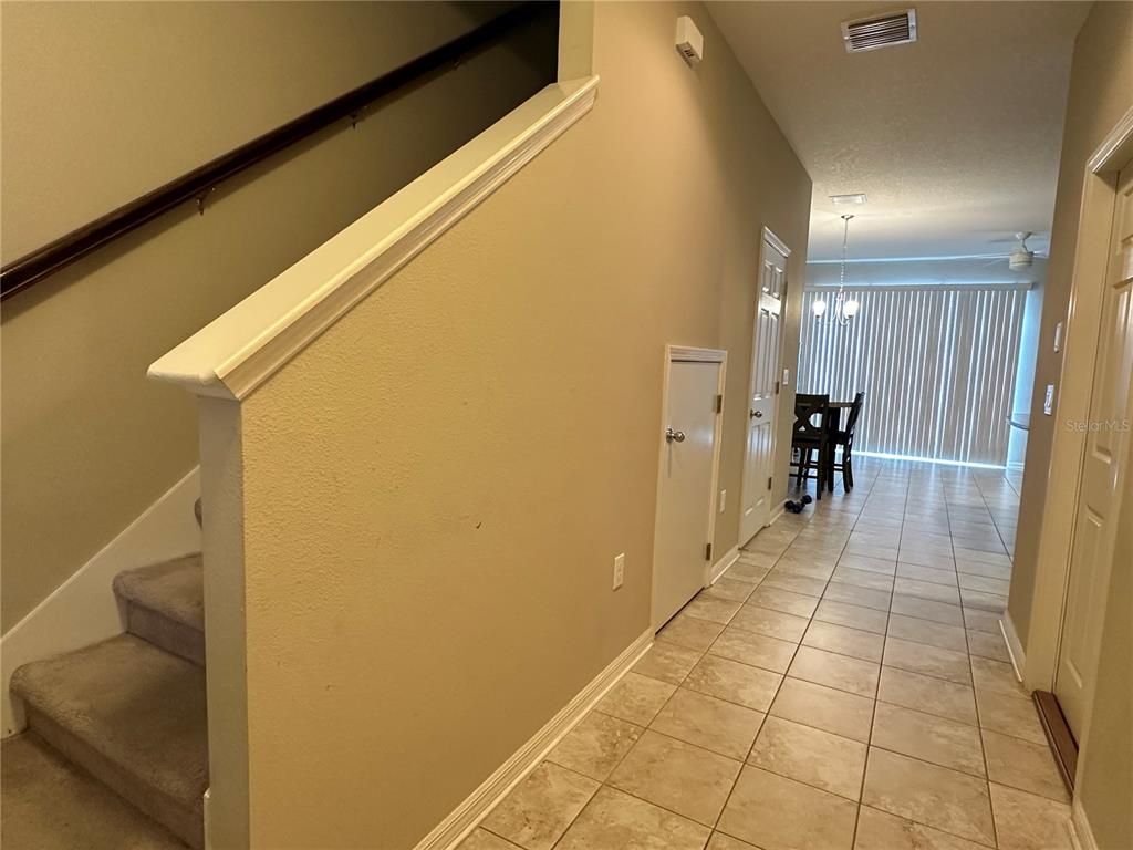 A tiled entryway leads to a staircase and a dining area with vertical blinds — 7089 WOODCHASE GLEN DRIVE, RIVERVIEW, FL