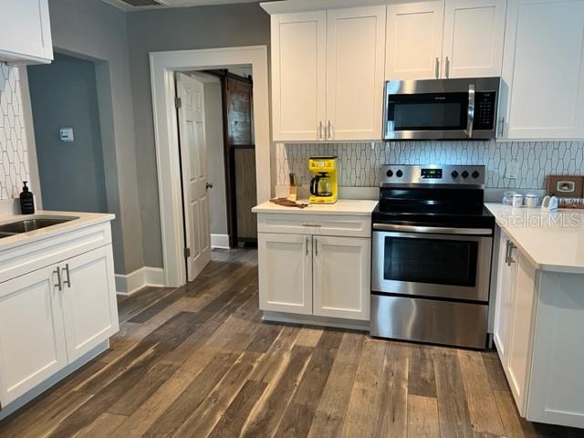 A kitchen features white cabinets, stainless steel appliances, and wood-look flooring — 1137 HIGHLAND STREET S, ST PETERSBURG, FL