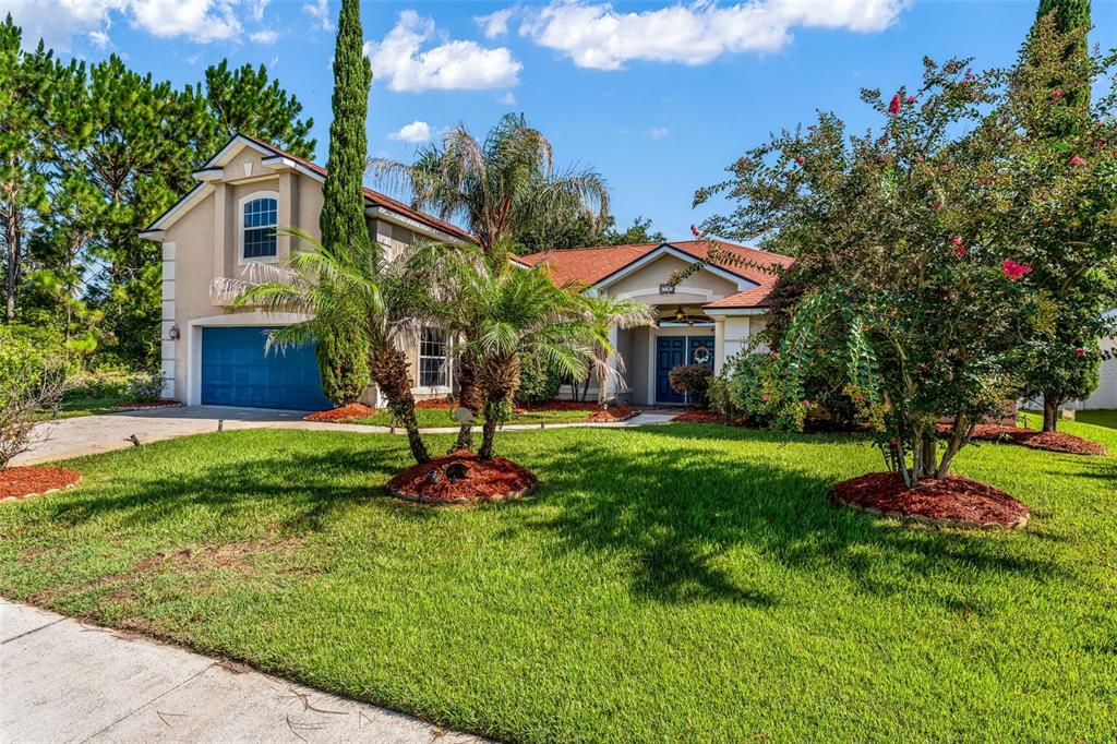 A two-story house with a blue garage door, palm trees, and a red shingled roof — 18 LEWISTON COURT, PALM COAST, FL