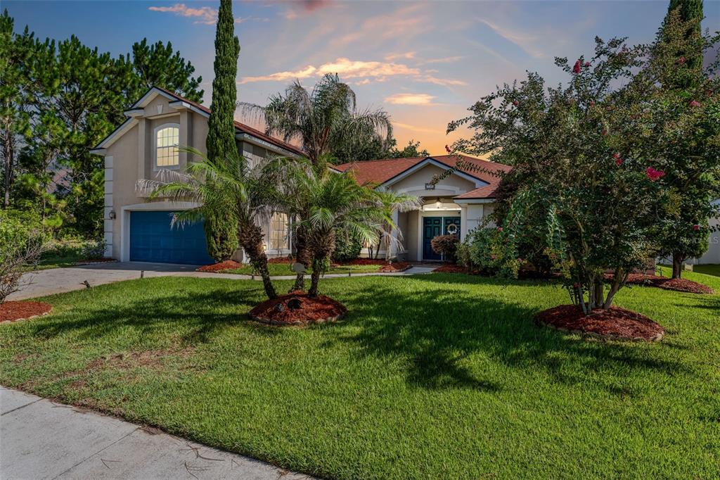 A two-story house with a blue garage door, red roof, and palm trees in front — 18 LEWISTON COURT, PALM COAST, FL