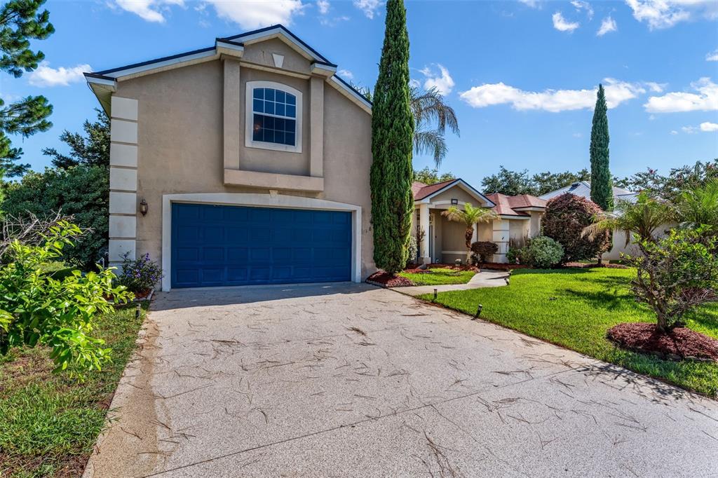 A two-story house with a blue garage door, beige stucco exterior, and a concrete driveway — 18 LEWISTON COURT, PALM COAST, FL
