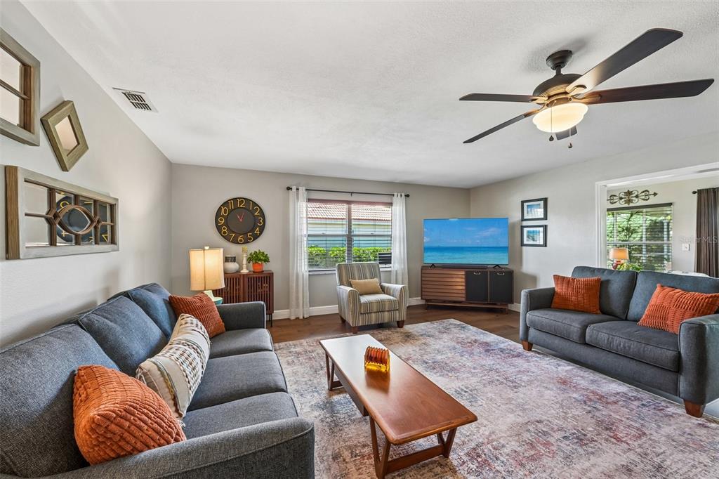 A living room features two gray sofas, a wooden coffee table, and a ceiling fan — 2025 NEW BEDFORD DRIVE, SUN CITY CENTER, FL