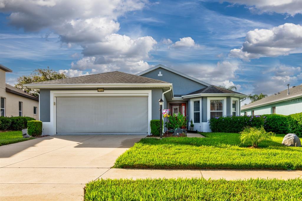 A single-story house with a gray exterior, a two-car garage, and a green lawn — 27336 PINE STRAW ROAD, LEESBURG, FL