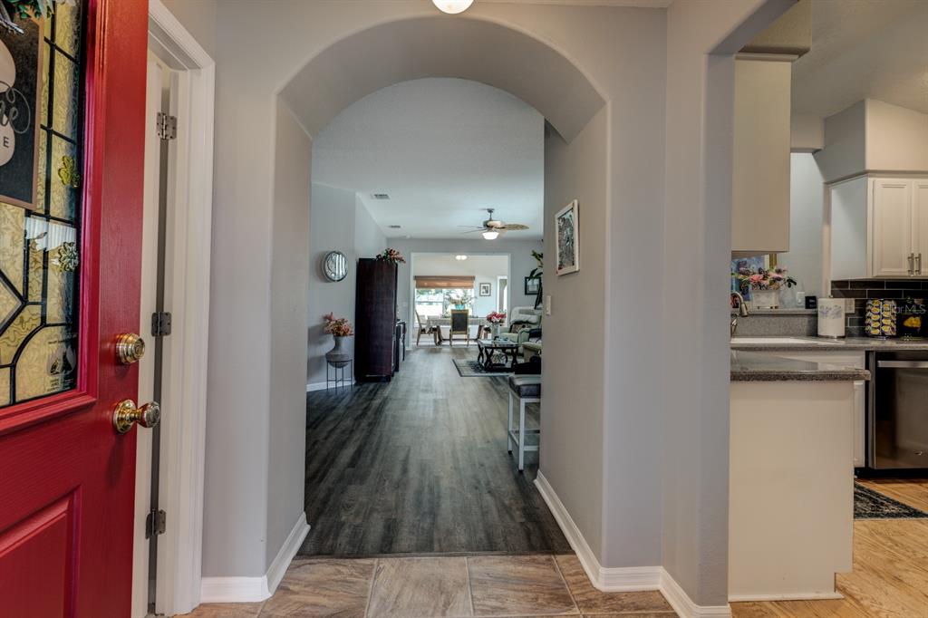 An entryway with a red door leads into a living area with wood-look flooring — 27336 PINE STRAW ROAD, LEESBURG, FL