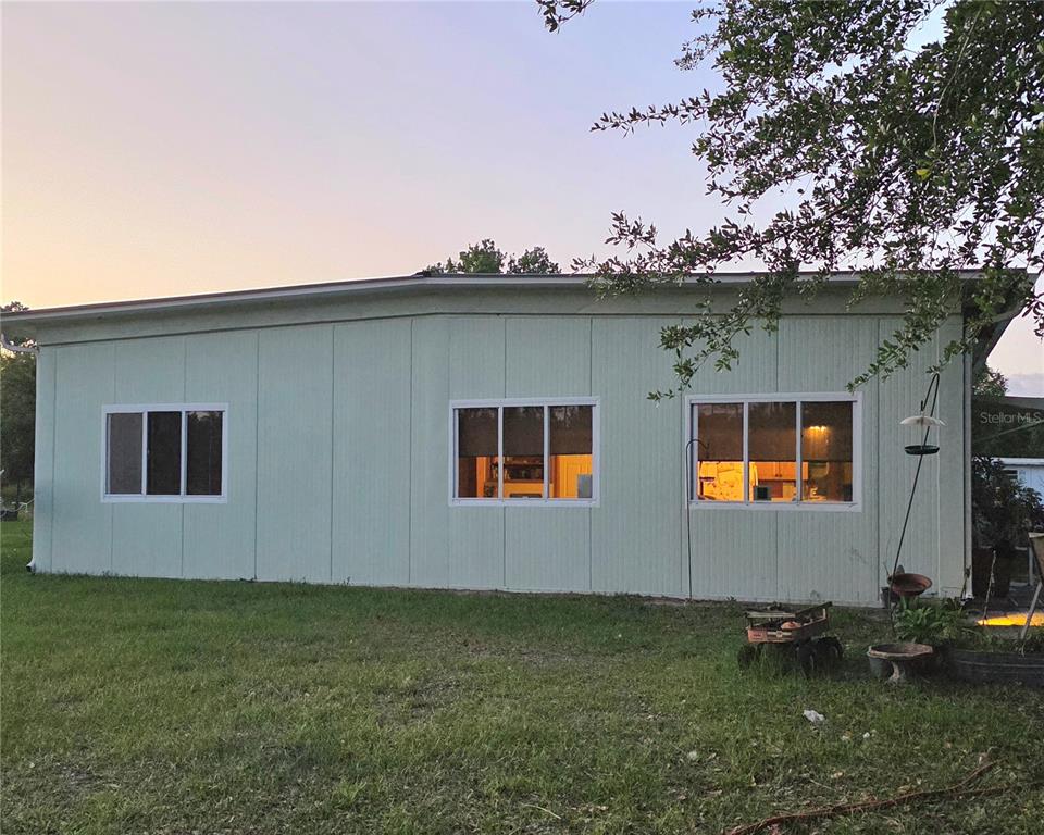 The exterior of a light green house with three windows sits on a grassy lawn — 54523 ASTOR TRANSFER STATION ROAD, ASTOR, FL