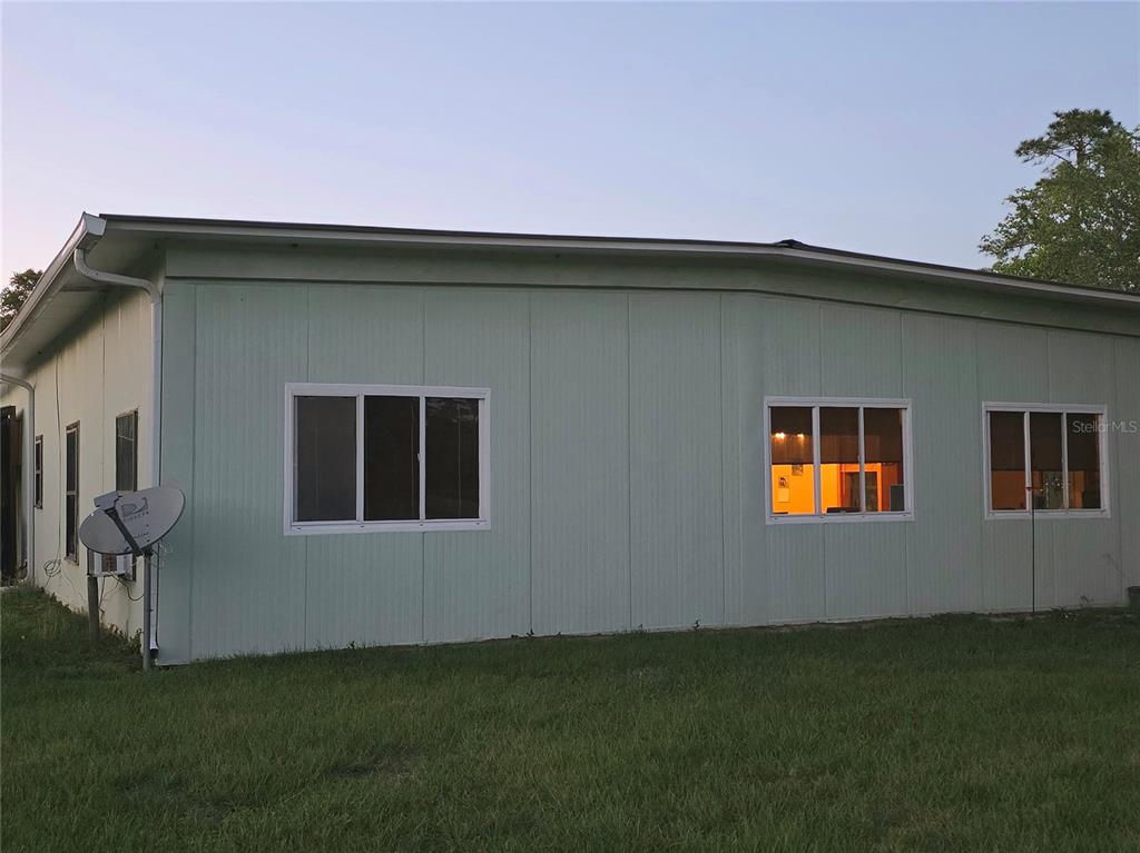 The exterior of a light green building features three windows and a satellite dish — 54523 ASTOR TRANSFER STATION ROAD, ASTOR, FL