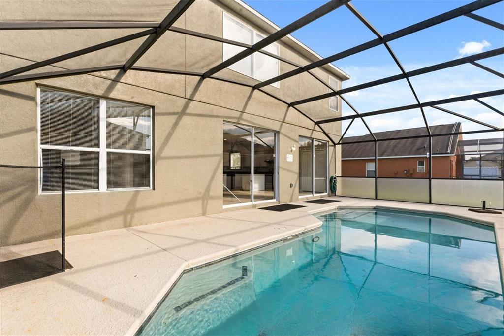 A bright living room features high ceilings, neutral furniture, a round coffee table, and large windows — 158 BAREFOOT BEACH WAY, KISSIMMEE, FL