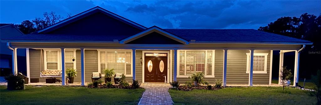 A single-story house with a covered front porch, dark siding, and a paved walkway at dusk — 5785 GILLIAM ROAD, ORLANDO, FL