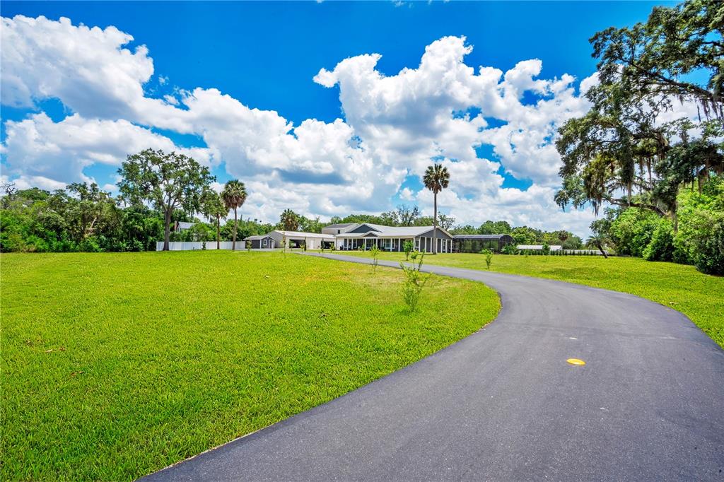A paved driveway leads to a single-story house surrounded by a large grassy lawn — 5785 GILLIAM ROAD, ORLANDO, FL