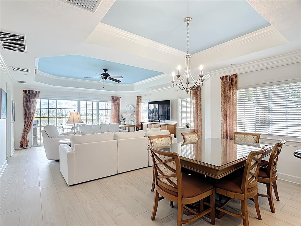 A living and dining area features a blue tray ceiling, white furniture, and tile flooring — 1362 CENTRE COURT RIDGE DRIVE UNIT 204, REUNION, FL