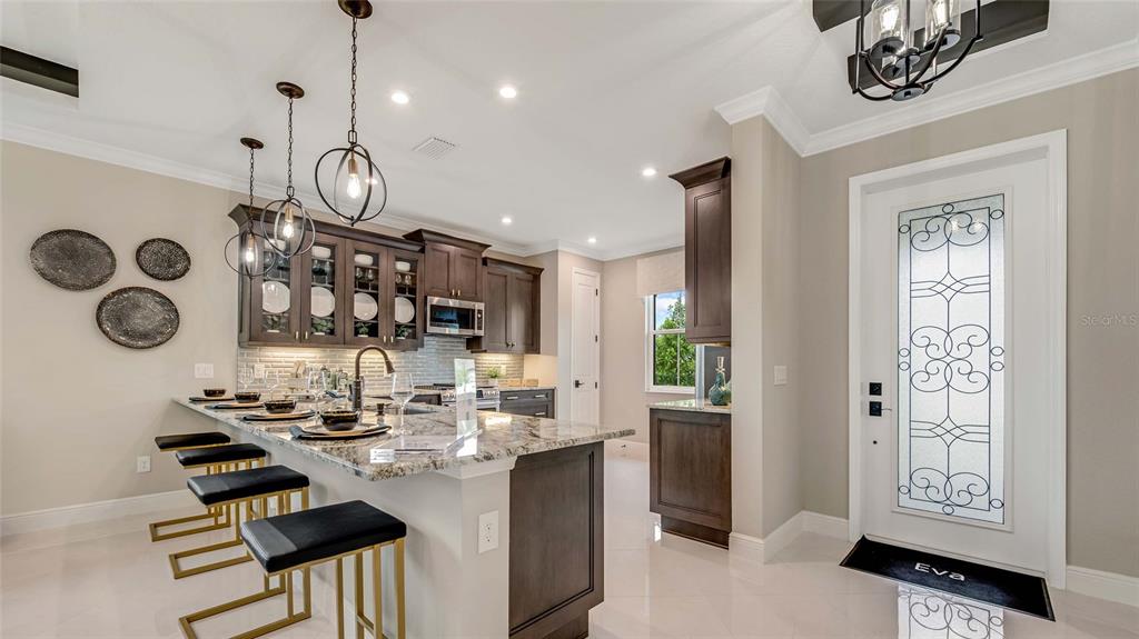A kitchen with dark wood cabinets, granite countertops, and a breakfast bar with gold stools — 1197 CRESSWIND BOULEVARD, DELAND, FL