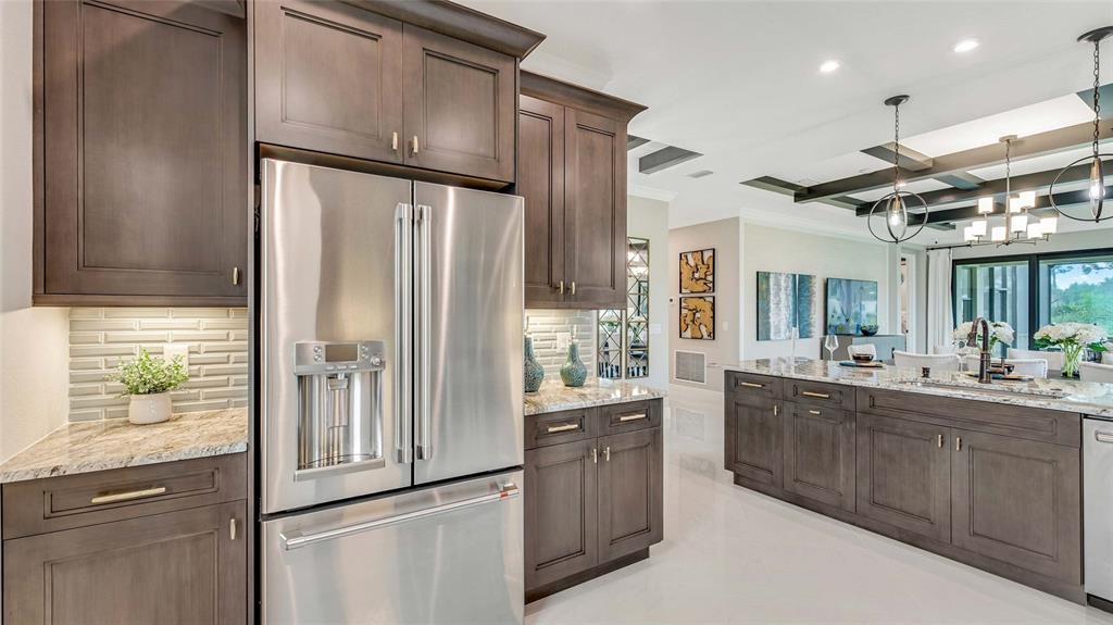 A modern kitchen features dark wood cabinetry, stainless steel appliances, and a large granite island — 1197 CRESSWIND BOULEVARD, DELAND, FL