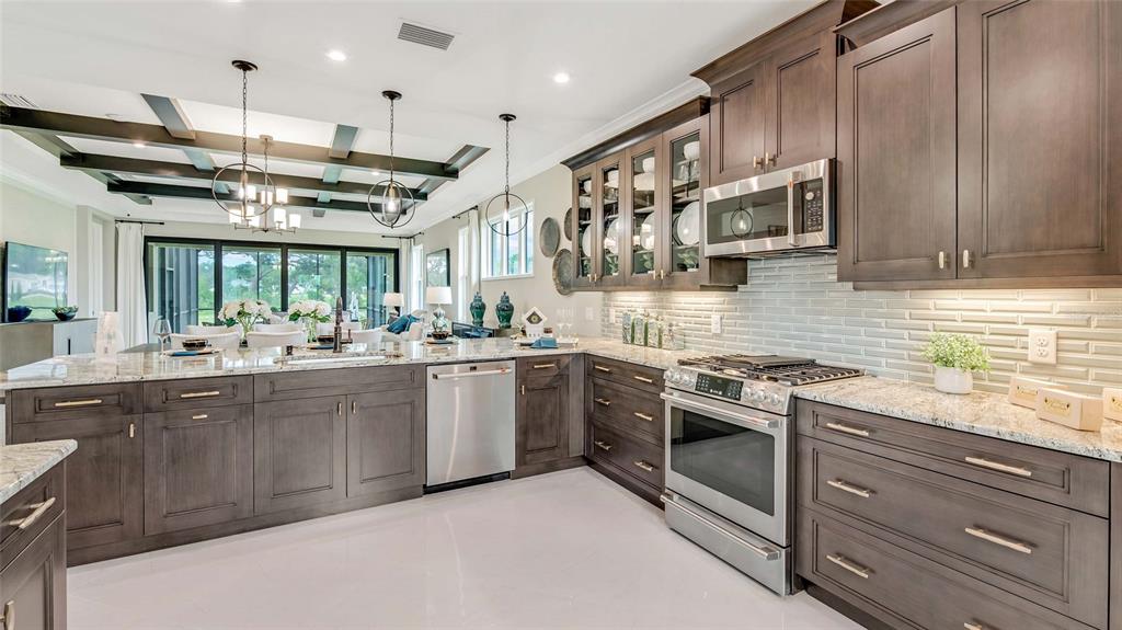 A modern kitchen features dark wood cabinetry, granite countertops, stainless steel appliances, and pendant lighting — 1197 CRESSWIND BOULEVARD, DELAND, FL