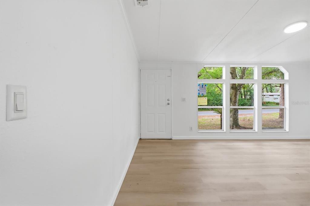 A bright room features white walls, light wood-look flooring, a white door, and large windows — 2565 E NORTH STREET, INVERNESS, FL