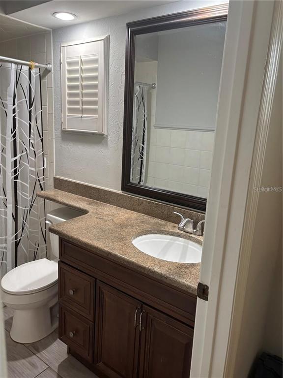 A bathroom features a dark wood vanity with a granite countertop, mirror, and toilet — 105 E COTTESMORE CIRCLE, LONGWOOD, FL