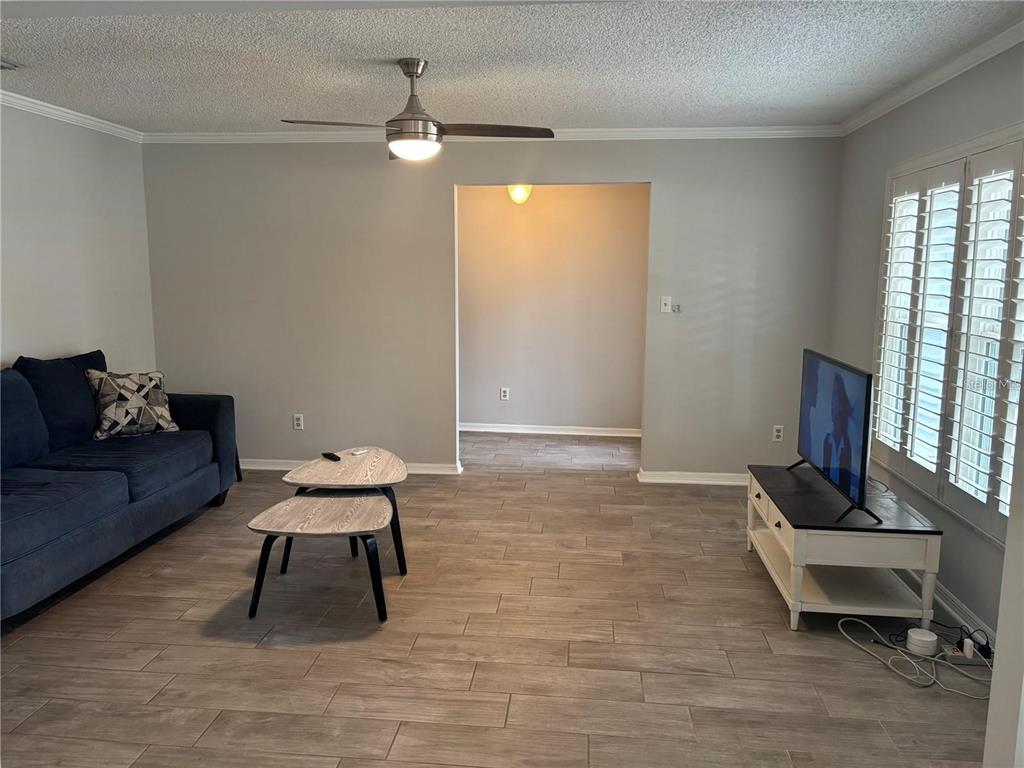 A living room with gray tile flooring, a blue sofa, and a ceiling fan — 105 E COTTESMORE CIRCLE, LONGWOOD, FL