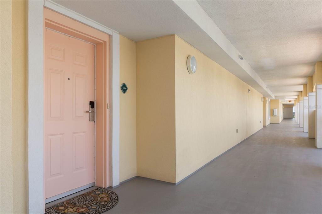 A pink door with a number plate sits along an outdoor apartment building walkway — 200 OCEAN CREST DRIVE UNIT 1016, PALM COAST, FL
