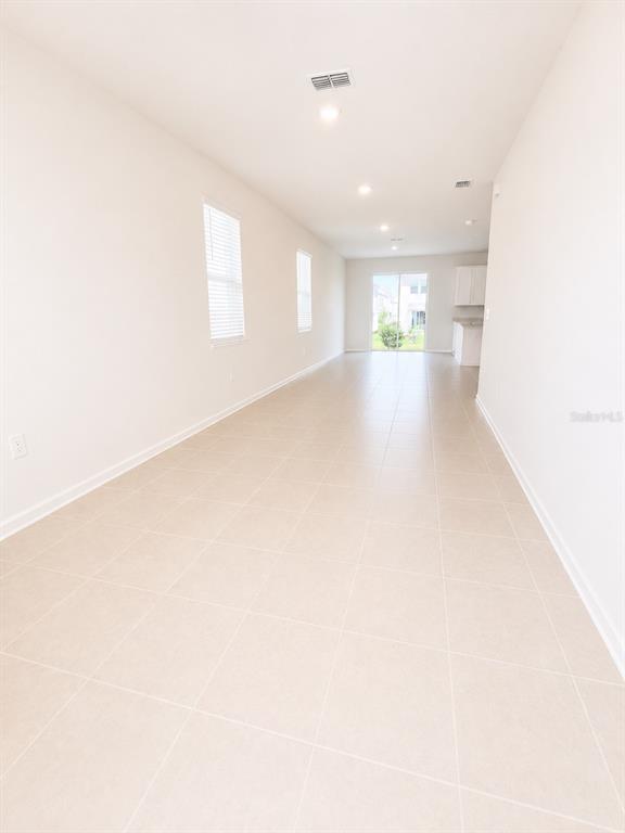 An empty room with light-colored tile flooring, white walls, and a sliding glass door — 3099 MINDFULLNESS DRIVE, CLERMONT, FL