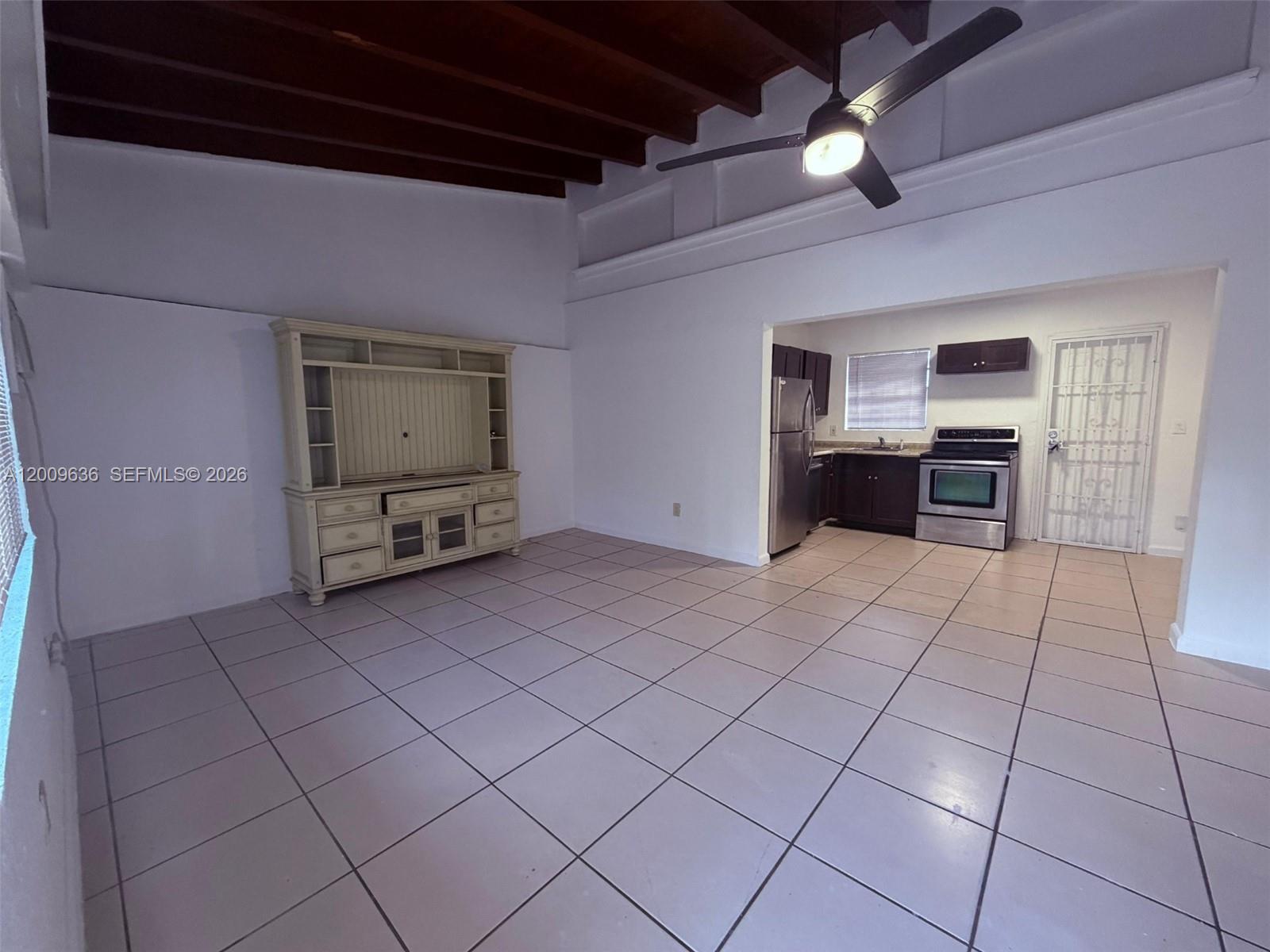 An open-concept living area features tile flooring, a vaulted wood-beam ceiling, and an adjoining kitchen — 590 NW 46th St # 2, Miami FL 33127, MIAMI, FL