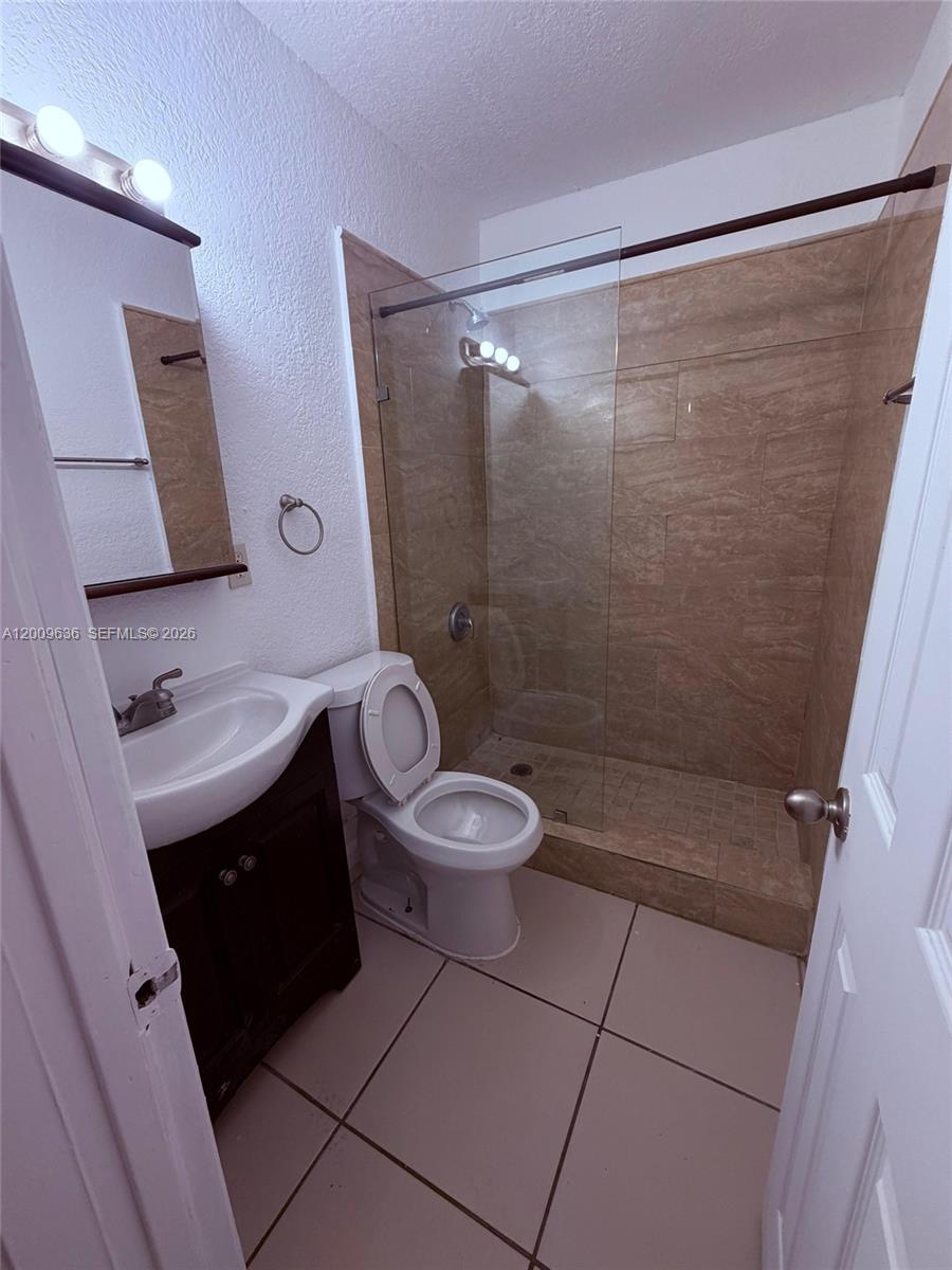 A bathroom features a vanity, a toilet, and a walk-in shower with tiled walls — 590 NW 46th St # 2, Miami FL 33127, MIAMI, FL