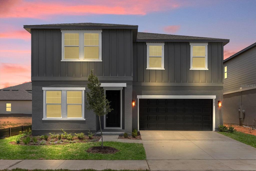 A two-story house with dark gray vertical siding, a black garage door, and a concrete driveway — 2306 LANCASHIRE STREET, DAVENPORT, FL