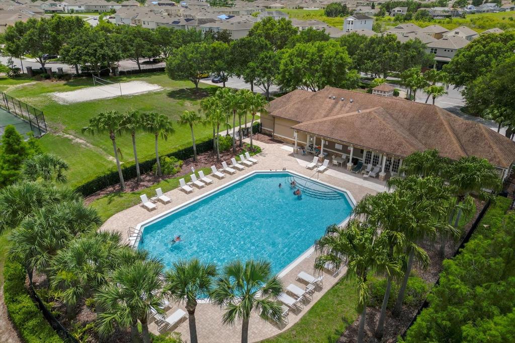 An aerial view shows a community swimming pool with lounge chairs, palm trees, and clubhouse — 2306 LANCASHIRE STREET, DAVENPORT, FL