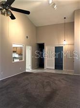 A living room with high ceilings, a ceiling fan, carpeted floors, and a pass-through window — 467 NEWTON PLACE, LONGWOOD, FL
