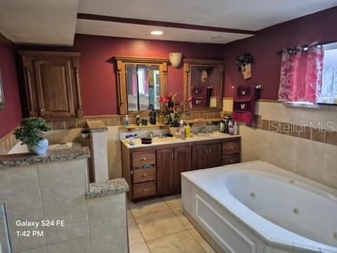 A bathroom features a jetted tub, double vanity with wood cabinets, and dark red walls — 6121 HOLIDAY HILL LANE, ORLANDO, FL