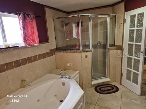A bathroom features a corner jetted tub, a glass-enclosed shower, and tiled walls and floors — 6121 HOLIDAY HILL LANE, ORLANDO, FL