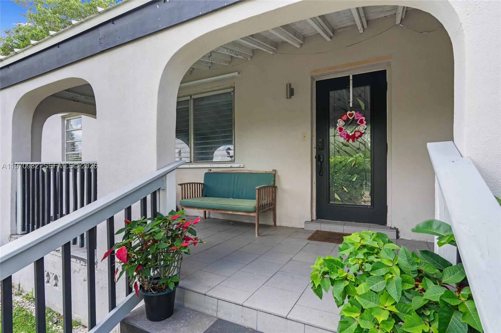 A covered front porch features a tiled floor, a wooden bench, and a glass-paneled door — 700 SW 44th Pl, Miami FL 33134, MIAMI, FL