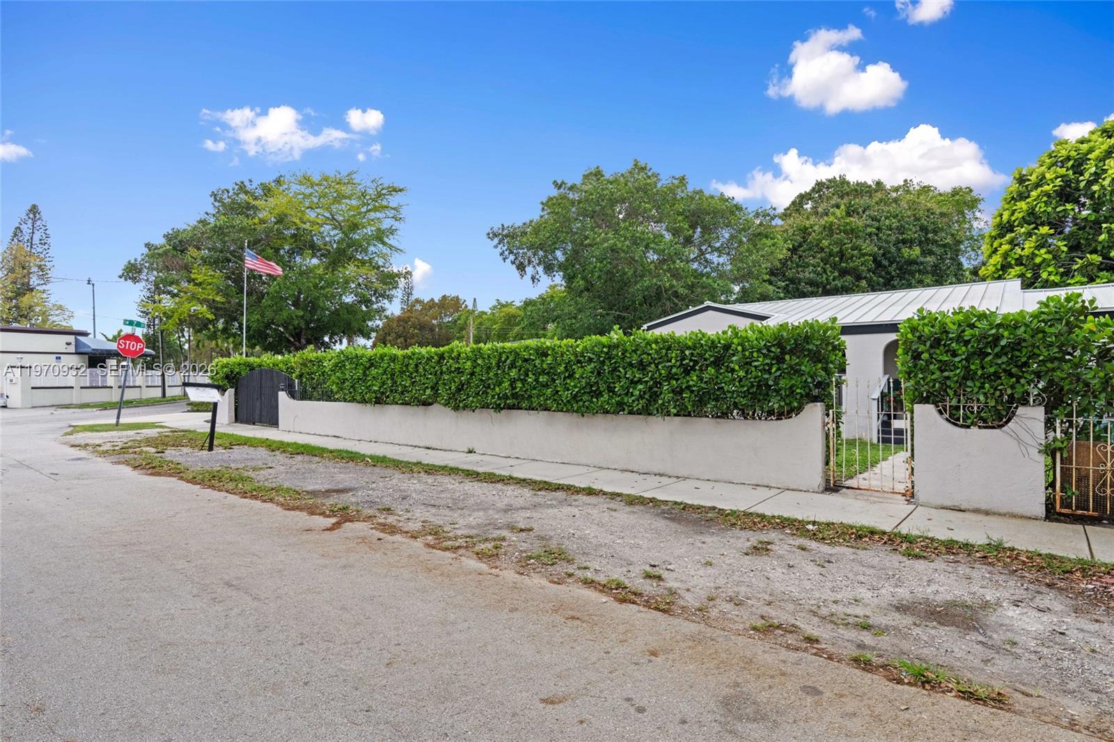 A white house is surrounded by a tall hedge and a concrete wall — 700 SW 44th Pl, Miami FL 33134, MIAMI, FL